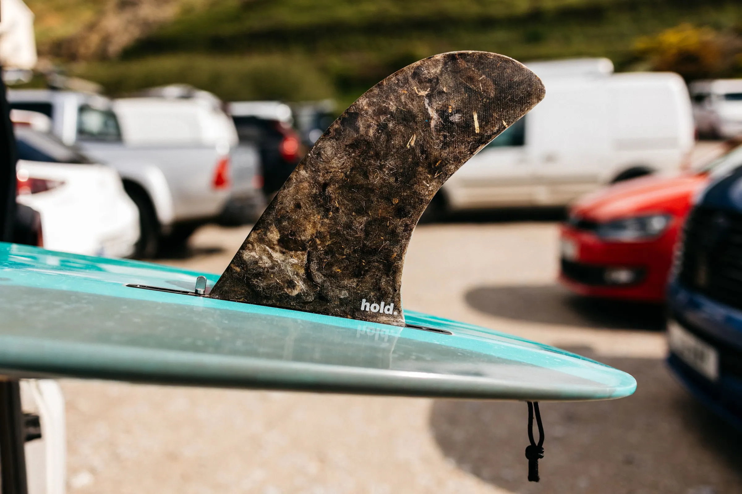 A Hold single fin fitted to a turquoise surfboard, showing the wool and reclaimed fibre texture.