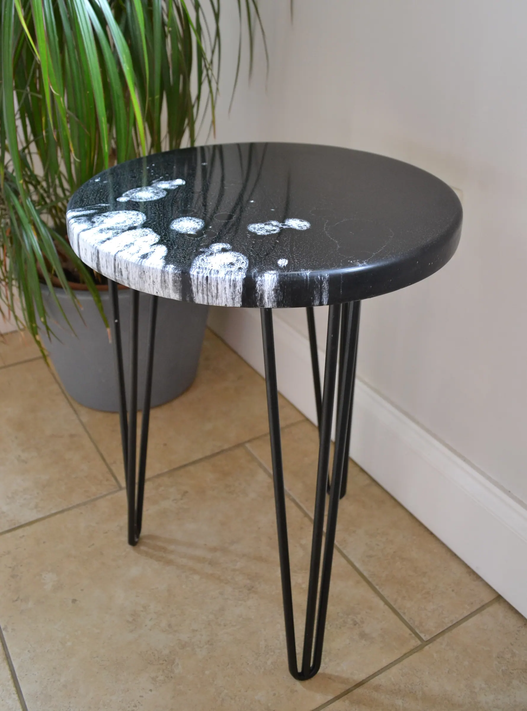 Black round side table made with surfboard fibreglass offcuts.