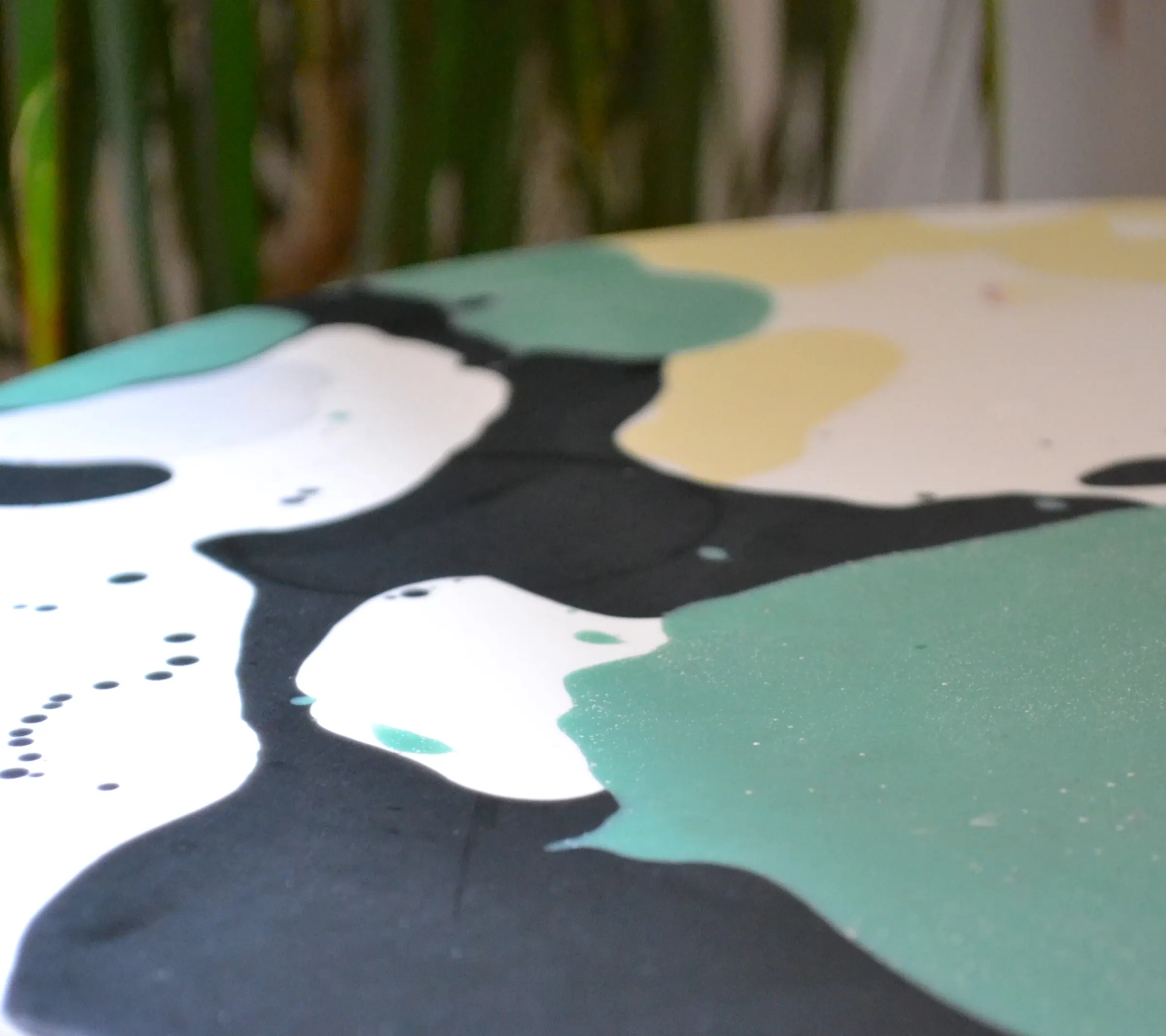 Close crop of green, white and black resin movement on a round tabletop.