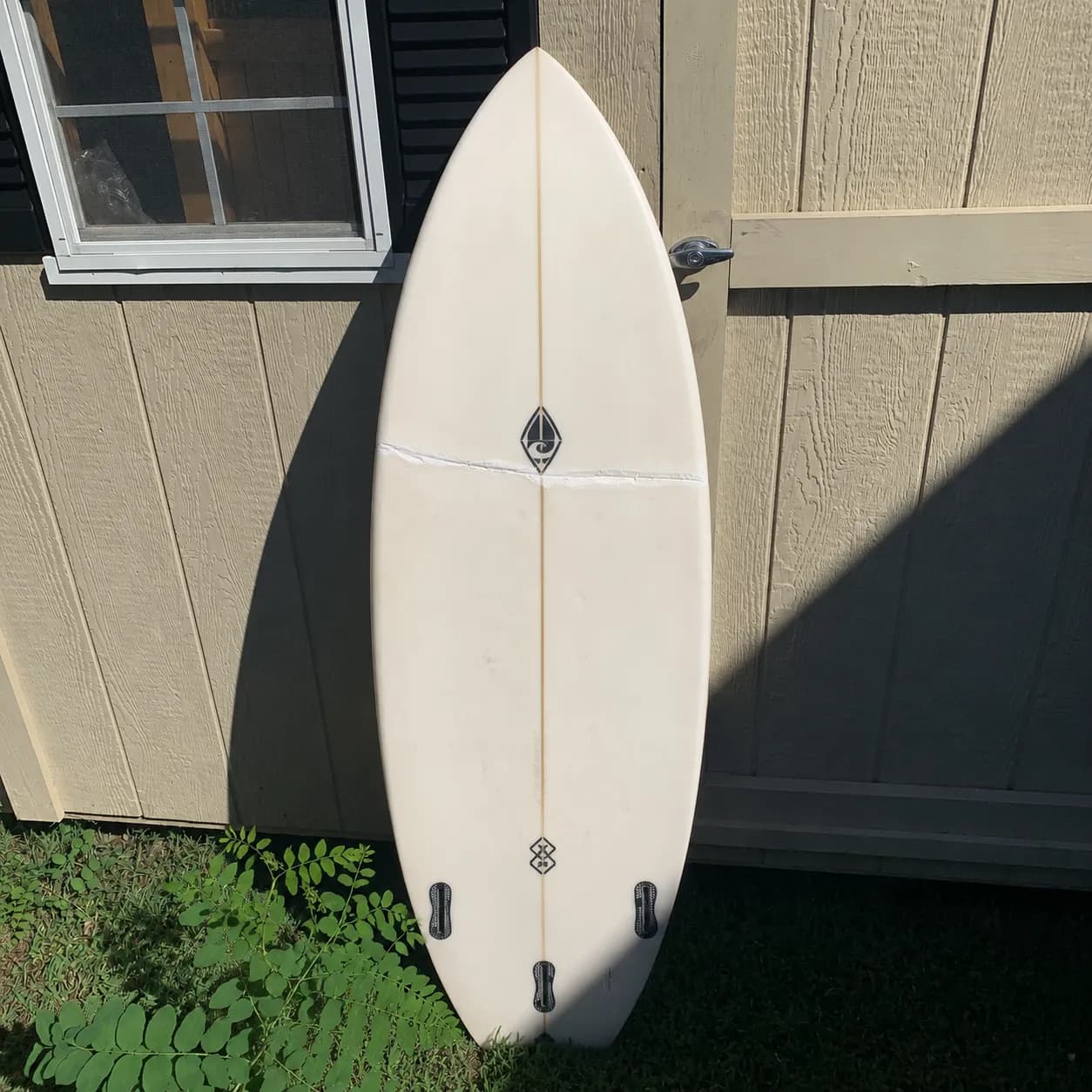 A buckled surfboard showing structural creasing across the deck before repair.