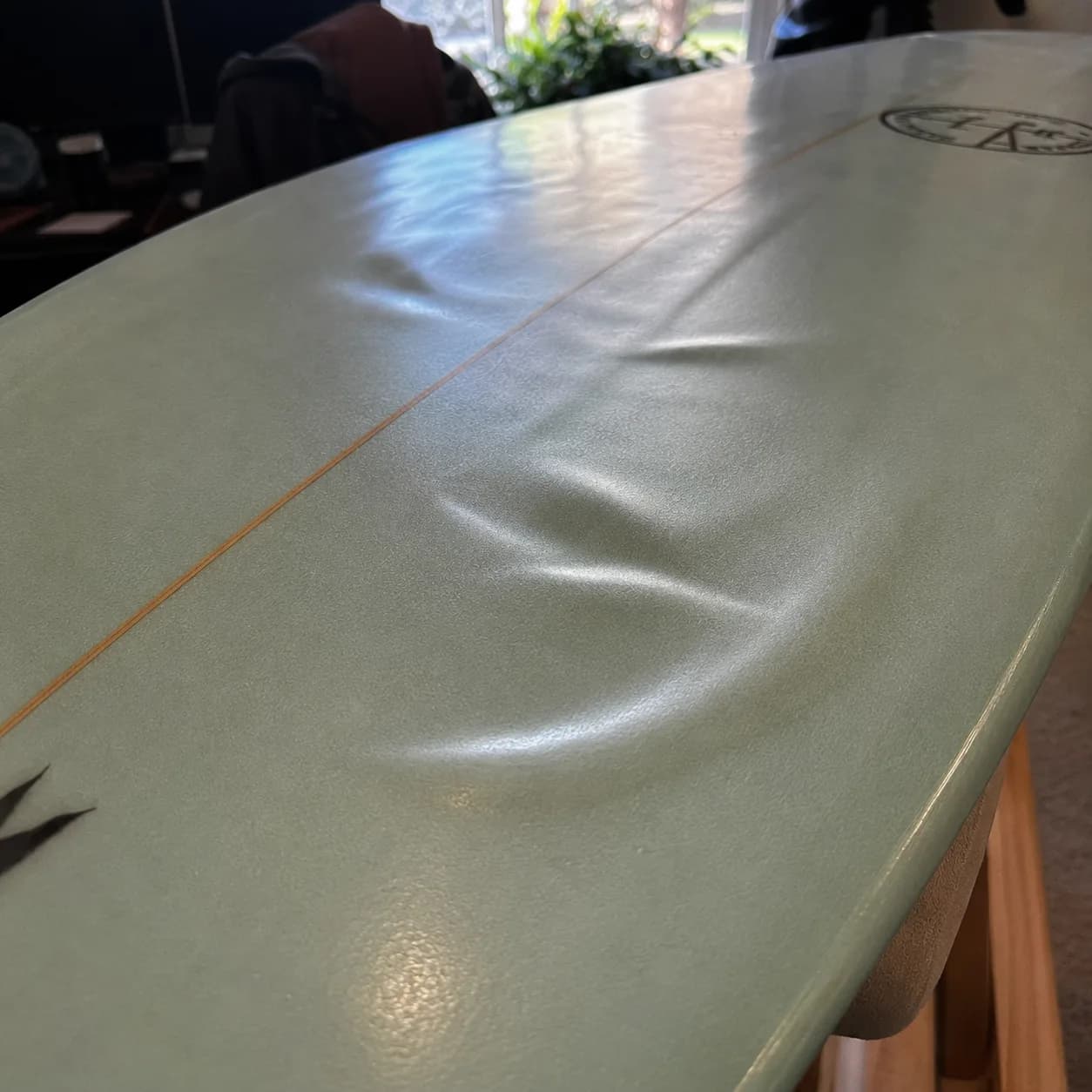 A delaminated surfboard deck with lifted glass before repair.