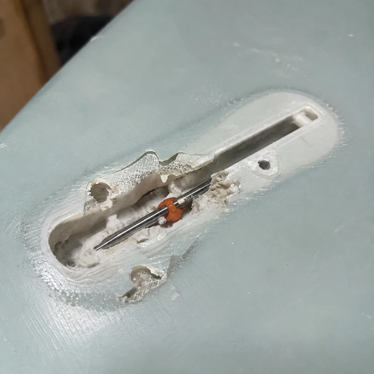 A broken fin box on a surfboard before repair.